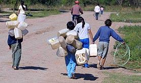 La gente lleva agua en Bidones.