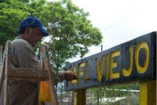 Alegría en el operario que repinta el cartel de la vieja estación    