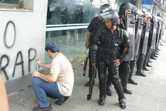 Policía observando a un puestero escrachando las paredes de la Municipalidad