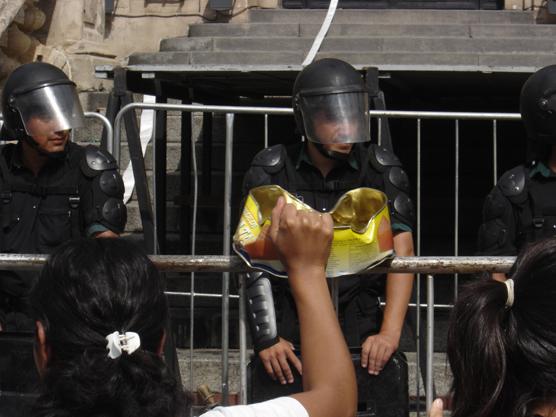 La policía miraba como los manifestantes se hacían sentir golpeando las vallas de seguridad con las latas