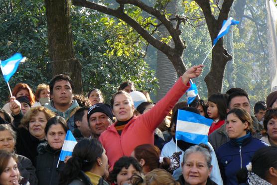 La gente que estaba en la Plaza Independencia saluda a los funcionarios agitando banderas argentinas 