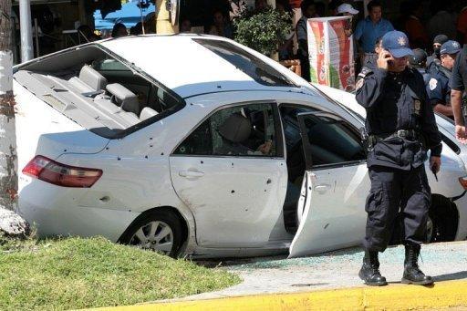 Un miembro de la Policía Federal junto a un coche tiroteado