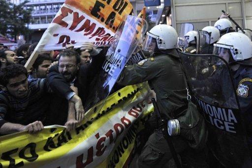 La policía antidisturbios empuja hacia atrás a manifestantes que bloquean la entrada al ministerio de Economía