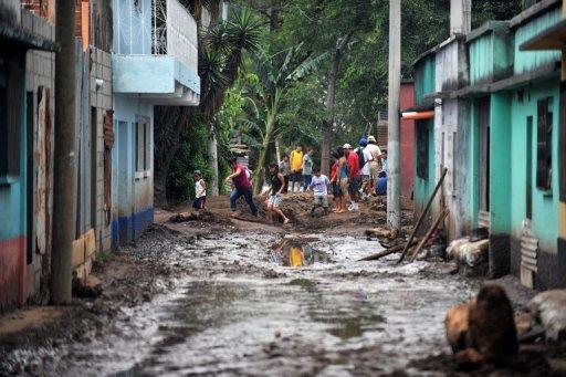 Un grupo de residentes caminan por las lodosas calles de Amatitlán, 35 kilómetros al sur de Ciudad de Guatemala