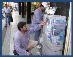 Operarios municipales despegando afiches