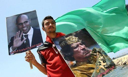 Un joven palestino sostiene en Gaza un cartel del líder libio Muamar Kadhafi (D) y su hijo Saif al-Islam