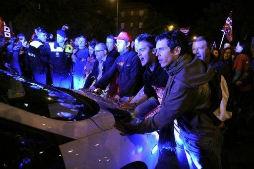 Unos manifestantes intentan bloquear un vehículo de la policía en Madrid