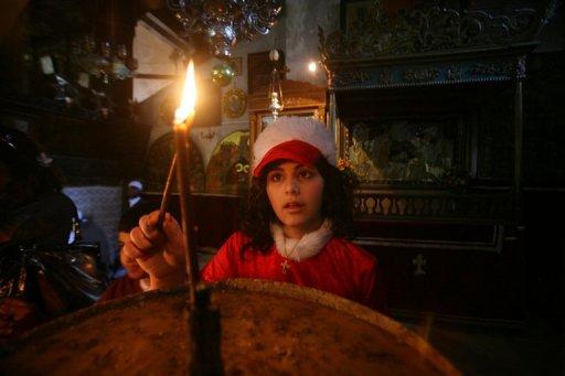 Una niña católica enciende una vela en Belén el 24 de diciembre. 