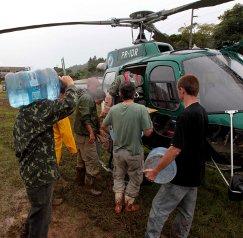 Un grupo de hombres carga agua y comida en un helicóptero en las afueras de Rio