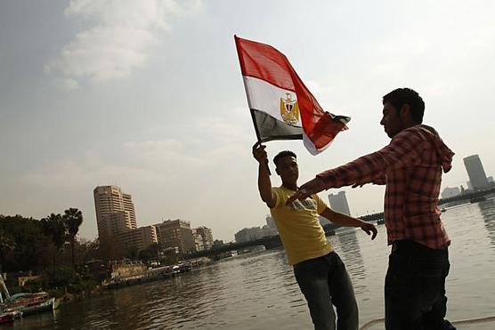 Jóvenes egipcios ondean una bandera nacional mientras bailan en un barco en el río Nilo en El Cairo