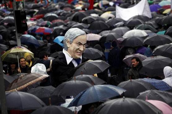 Un muñeco del presidente de Chile, Sebastián Piñera, es visto entre miles de personas que marchan bajo la lluvia