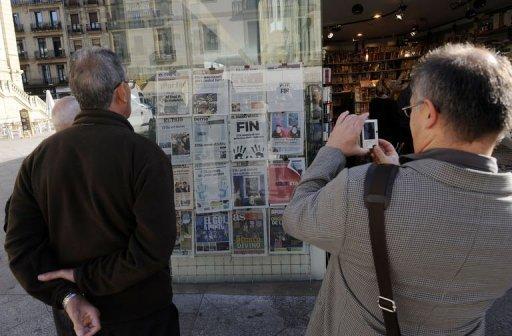 Una persona fotografía en San Sebastián las portadas de los periódicos