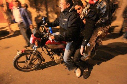 Dos manifestantes egicpios evacúan a un herido cuando la policía les arrojó gases lacrimógenos, en El Cairo este jueves