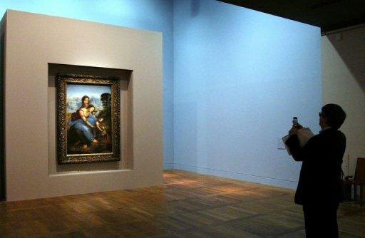 Un visitante toma una fotografía del cuadro 'Santa Ana con la Virgen y el Niño' de Da Vinci