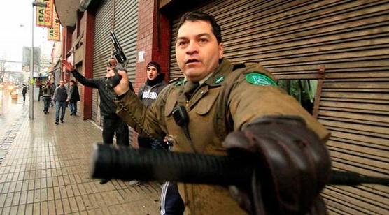 Carabinero empuñando un arma frente a la marcha