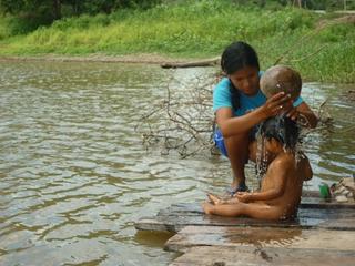 Una mujer baña a su hijo en el río