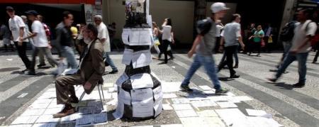 Empleado apoyado en un poste con carteles ofreciendo empleos en Sao Paulo