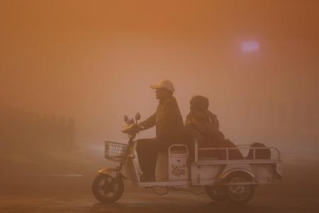 Dos personas atraviesan la neblina en motocarro