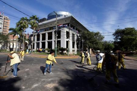 Empleados muncipales limpian los alrededor del Congreso quemado