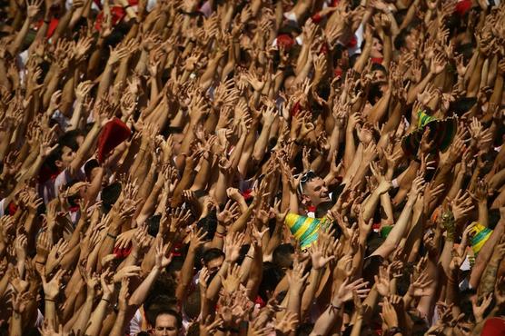 Juerguistas levantan los brazos durante el lanzamiento del cohete "chupinazo"