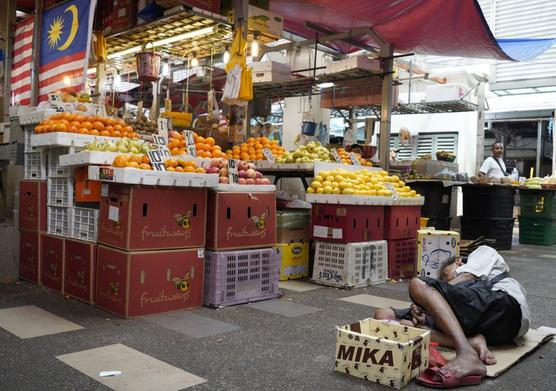 Un changarín duerme en el piso de un mercado en Kampung Baru, Malasia.