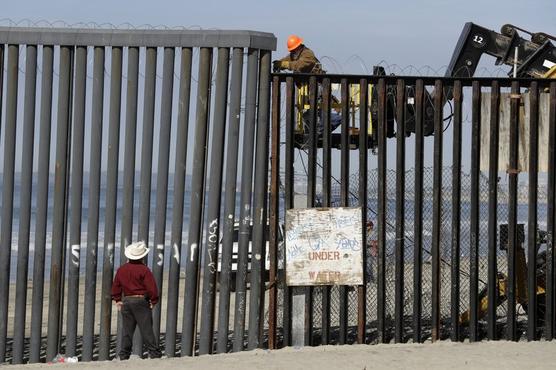 Migrantes en el muro fronterizo