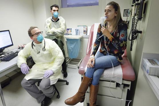 Los doctores Jon Koff  y Benjamin Chang observan a la paciente Ella Balasa inhalar un bacteriófago producido por Chang 