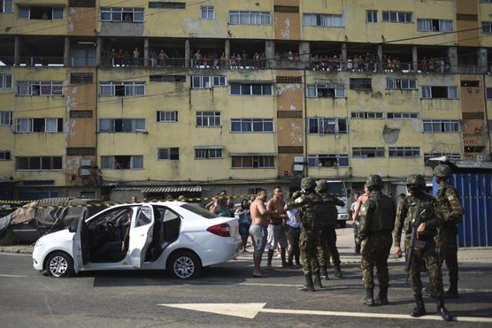 Los vecinos observan las acciones de los militares en el lugar del crimen