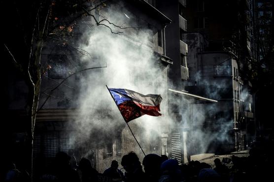 Manifestantes alzan una bandera chilena durante una protesta contra el gobierno en Santiago
