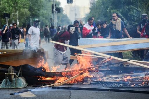 Manifestantes instalan una barricada durante los enfrentamientos con la policía antidisturbios, en las protestas sociales