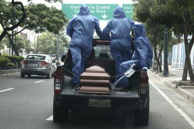 Trabajadores de cementerio usan equipo de protección y transportan los restos de una persona