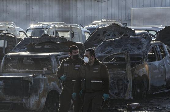 La policía pasa junto a vehículos incendiados dentro de un concesionario de automóviles en la noche del martes 