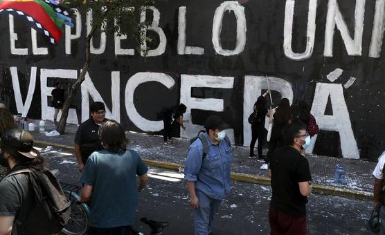 Manifestantes pintan una pared mientras conmemoran el aniversario del estallido social de 2019