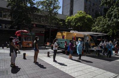 Personas en fila para hacerse una prueba rápida de COVID-19 en una unidad móvil en el centro de Santiago