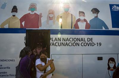 Mujeres salen de un autobús que se usa para inyectar la vacuna contra COVID-19 en Santiago