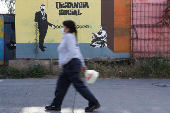 Una mujer pasa junto a un grafiti que dice 'Distancia social'