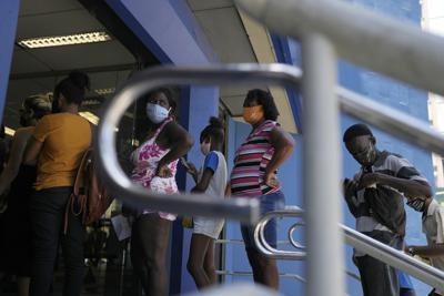 Personas hacen fila para retirar dinero de un programa de asistencia social en un banco público