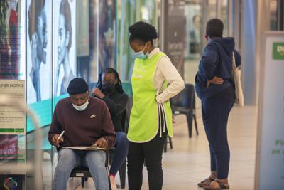 Varias personas esperan para vacunarse contra el COVID-19 en un centro comercial en Johannesburgo, Sudáfrica