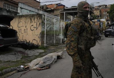 Un soldado monta guardia junto al cadáver de un hombre que murió en una redada policial de presuntos narcotraficantes