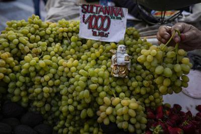 Una estatua de Buda descansa sobre uvas a la venta por un vendedor ambulante en el centro de Santiago 