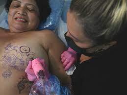 La tatuadora brasileña Karlla Mendes dibuja una de sus creaciones en el cuerpo de Marlene Santos,