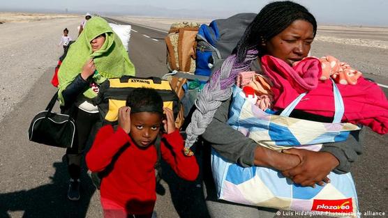 Una familia de migrantes venezolanos camina sobre la vía fronteriza entre Bolivia y Chile que conduce a Colchane