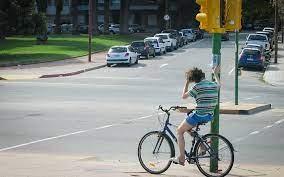 Un ciclista se sostiene de un semáforo en el cruce de una avenida en Montevideo 