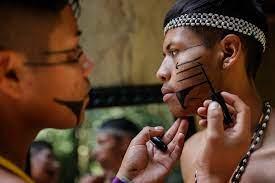 Indígenas de la etnia Guarani se pintan la cara durante el desfile de la marca de ropa Kunhague Rembiapó Rendá.