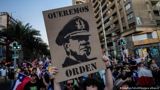 Manifestantes expresan con una pancarta con la imagen de Pinochet querer "orden"