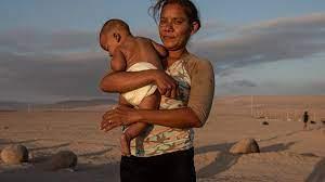 Jimir Coromoto sostiene a su hijo mientras esperan soluciones a su situación migratoria, en el paso fronterizo Chacalluta