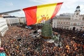 Un manifestante sostiene una bandera de España desde un balcón en la plaza de la Puerta del Sol - © OSCAR DEL POZO / AFP 