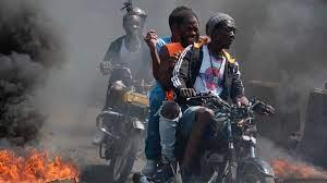 Hombres a bordo de motocicletas pasan junto a neumáticos incendiados en una manifestación en Puerto Principe - AFP