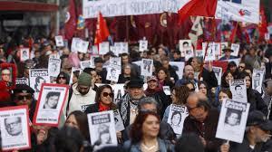 Manifestantes sostienen fotografías de personas desaparecidas dumarcha de conmemoración del 51 aniversario del golpe militar AFP